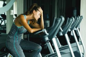 Ragazza stanca sulla cyclette in palestra