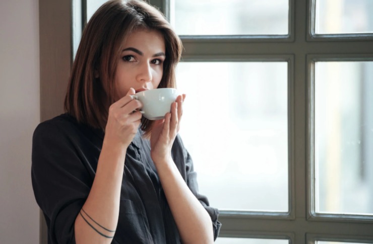 donna che beve un caffè accanto ad una finestra