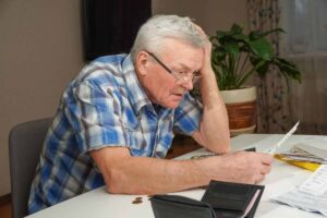 Pensionato legge un documento, sconvolto