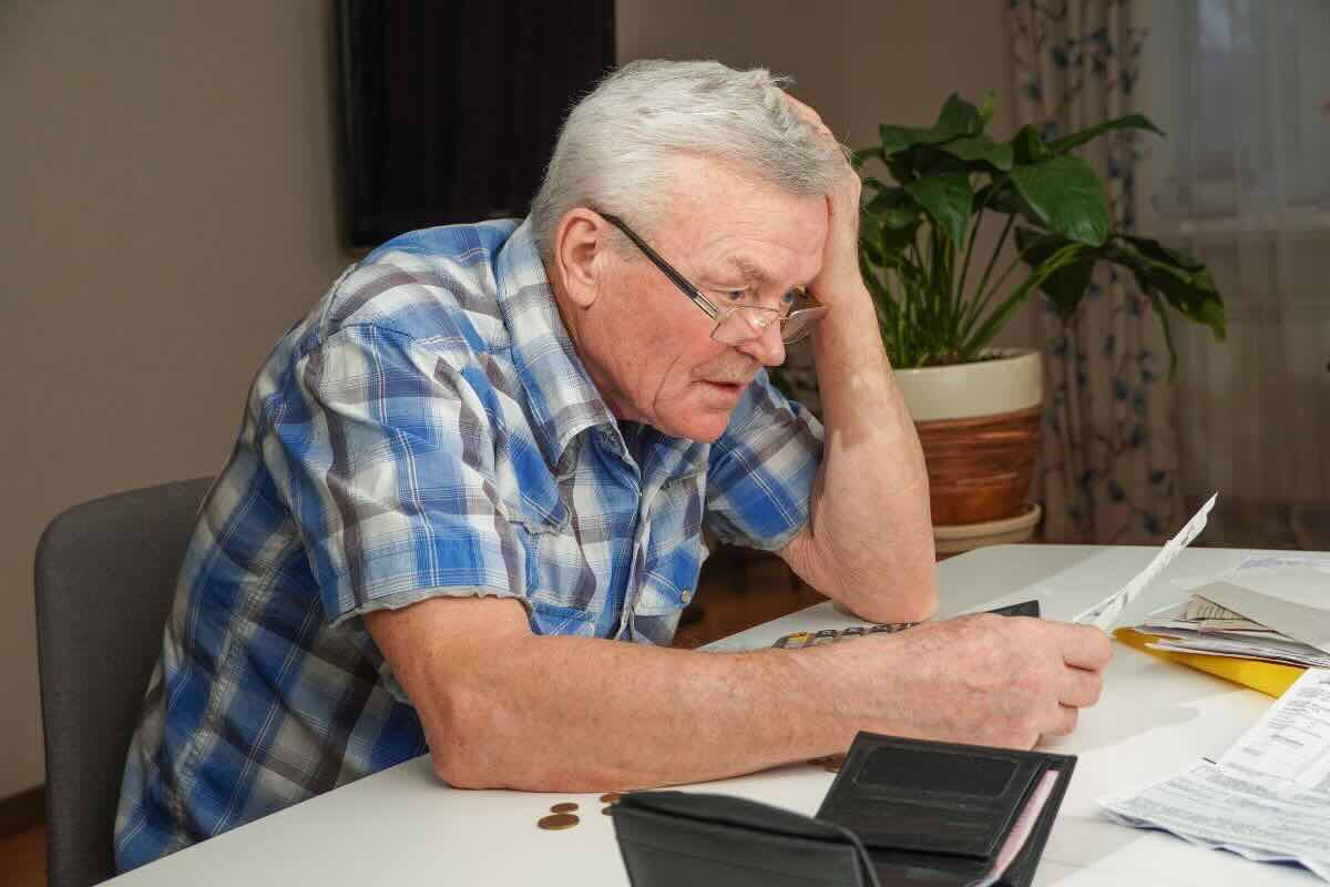 Pensionato legge un documento, sconvolto